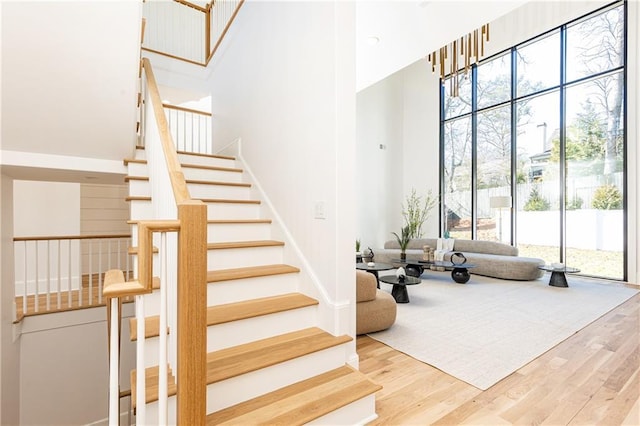 stairs featuring hardwood / wood-style floors and a high ceiling