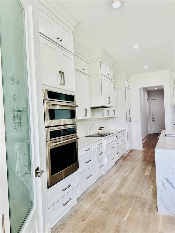 2964 Old Peachtree Rd, Dacula, GA 30019 - kitchen featuring light wood-style floors, black electric stovetop, recessed lighting, stainless steel double oven, and white cabinetry