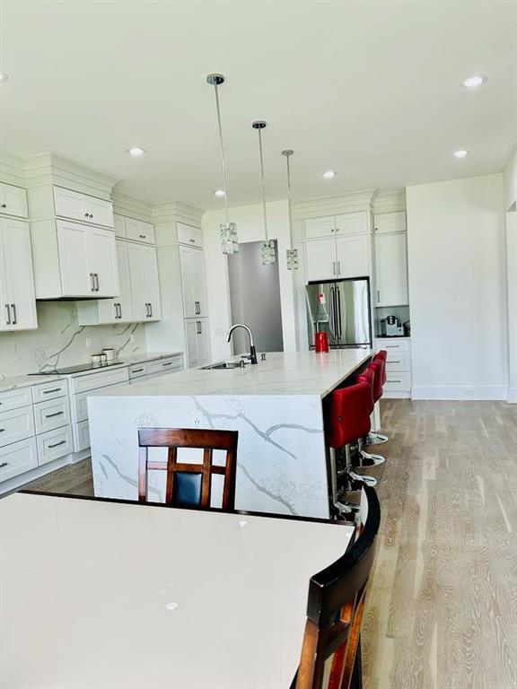 2964 Old Peachtree Rd, Dacula, GA 30019 - kitchen with a kitchen breakfast bar, stainless steel refrigerator with ice dispenser, light wood-type flooring, white cabinets, and a sink