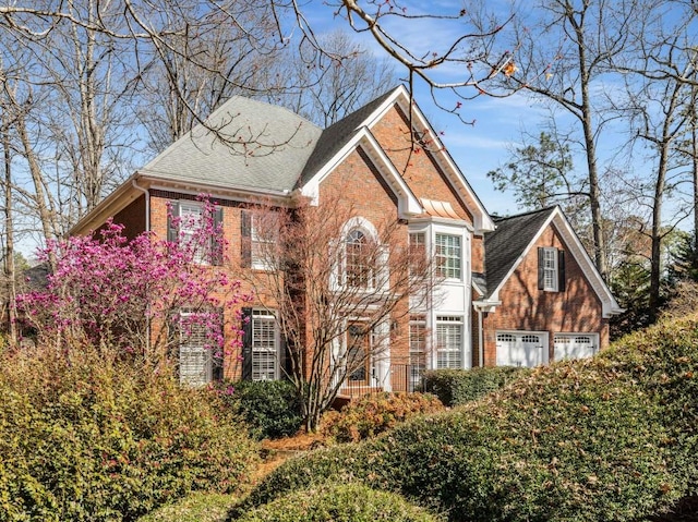 view of front of house featuring brick siding and a shingled roof