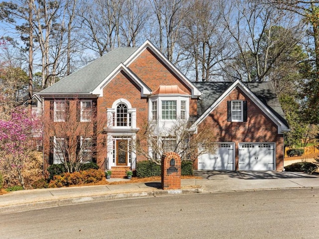 colonial house featuring a garage, brick siding, and driveway