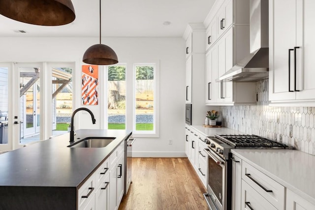 kitchen with visible vents, light wood-type flooring, a sink, appliances with stainless steel finishes, and wall chimney range hood