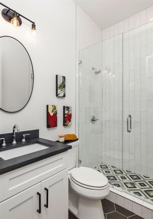 bathroom with tile patterned floors, vanity, toilet, and a shower stall