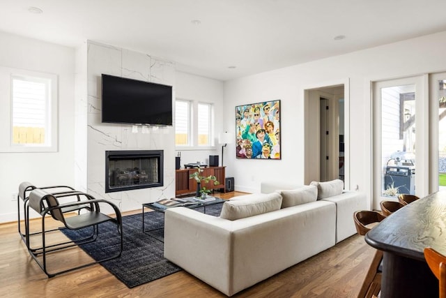 living area with wood finished floors, baseboards, and a high end fireplace