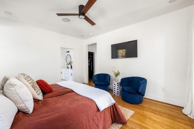 bedroom featuring light wood-style flooring, a ceiling fan, ensuite bathroom, and baseboards