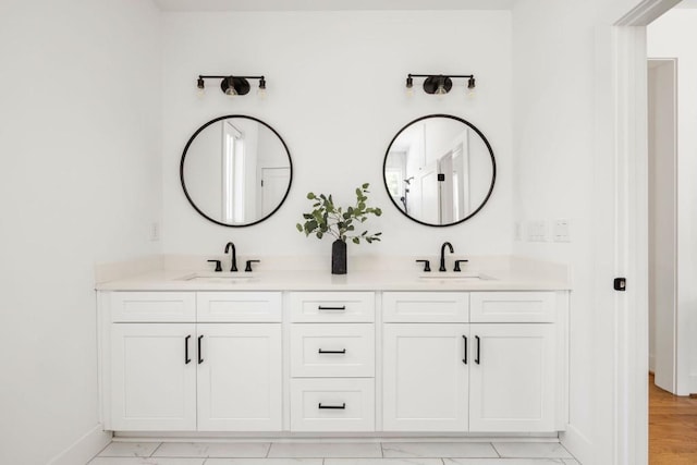 full bathroom with double vanity, baseboards, and a sink