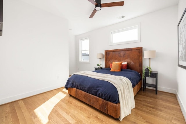 bedroom with visible vents, baseboards, wood finished floors, and a ceiling fan