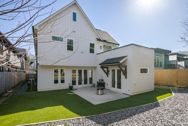 back of property with board and batten siding, french doors, a yard, a fenced backyard, and a patio