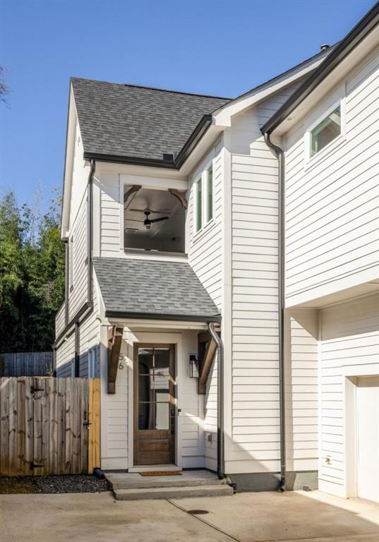 townhome / multi-family property with driveway, roof with shingles, and fence