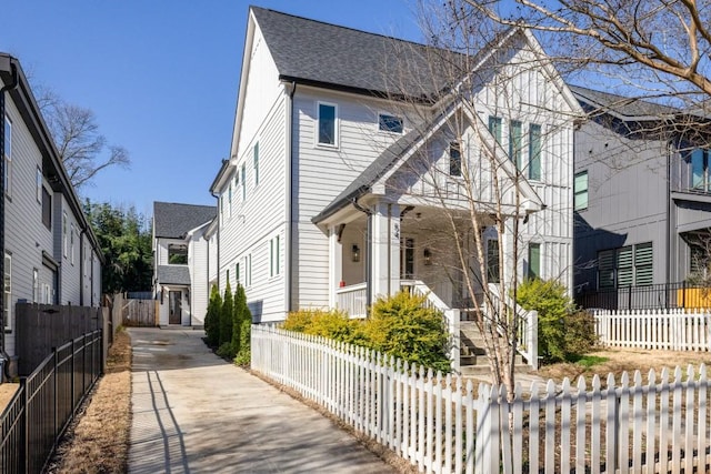 view of front of house featuring a fenced front yard and a shingled roof