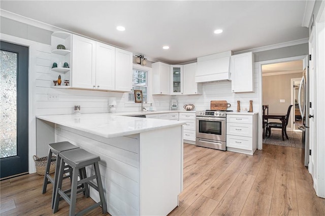 kitchen featuring white cabinetry, custom exhaust hood, stainless steel appliances, and a breakfast bar area