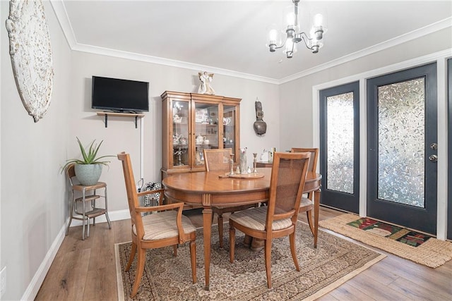 dining area with an inviting chandelier, hardwood / wood-style floors, and ornamental molding