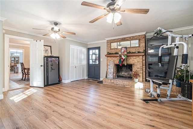 unfurnished living room with ornamental molding, ceiling fan, a fireplace, and light wood-type flooring