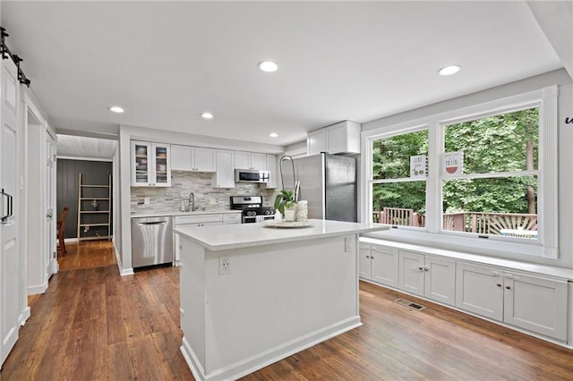 9470 Hillside Dr, Roswell, GA 30076 - kitchen with stainless steel appliances, white cabinets, light countertops, wood finished floors, and glass insert cabinets