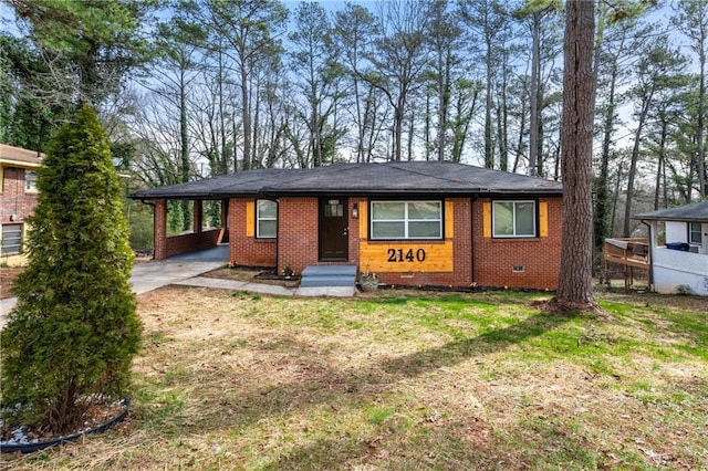 view of front facade with an attached carport, brick siding, driveway, crawl space, and a front yard