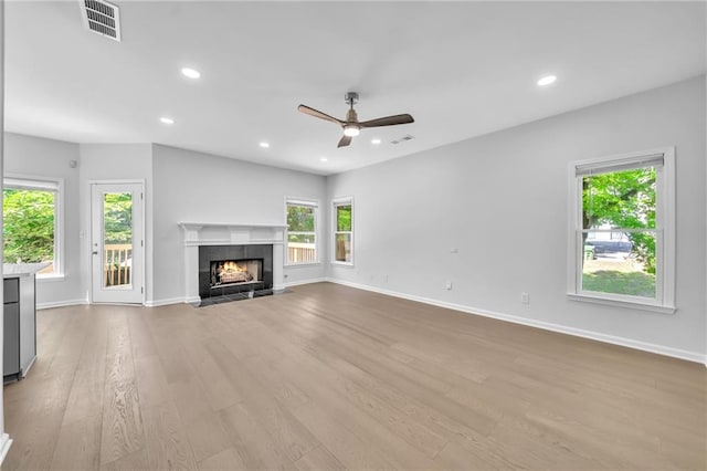 unfurnished living room featuring ceiling fan, a fireplace, and light hardwood / wood-style flooring