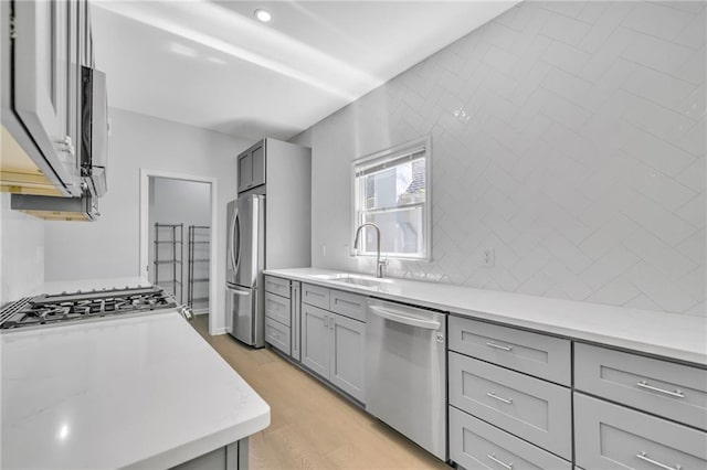 kitchen featuring gray cabinets, sink, appliances with stainless steel finishes, and light hardwood / wood-style flooring