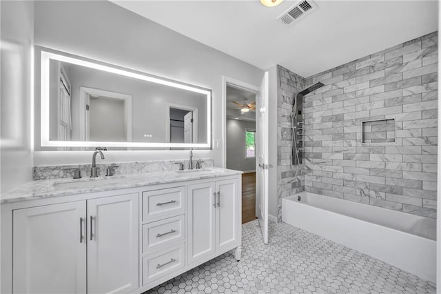 bathroom with ceiling fan, tiled shower / bath, and vanity