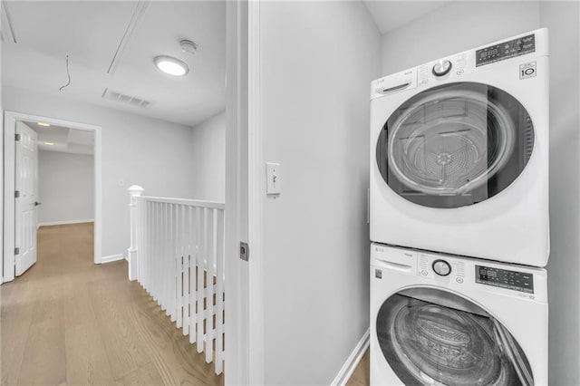 laundry area with light wood-type flooring and stacked washing maching and dryer