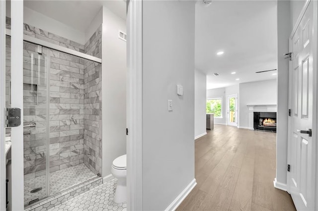 bathroom with hardwood / wood-style flooring, vanity, a shower with shower door, and toilet