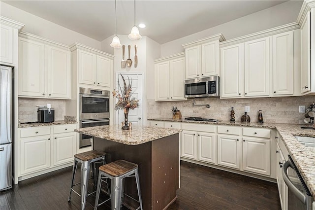 kitchen featuring decorative light fixtures, appliances with stainless steel finishes, white cabinetry, and decorative backsplash