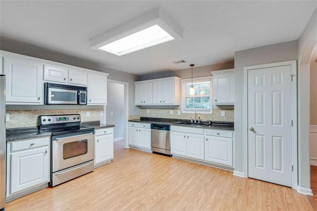 1227 Casper Ln, Winder, GA 30680 - kitchen with appliances with stainless steel finishes, a sink, dark countertops, light wood-type flooring, and white cabinets