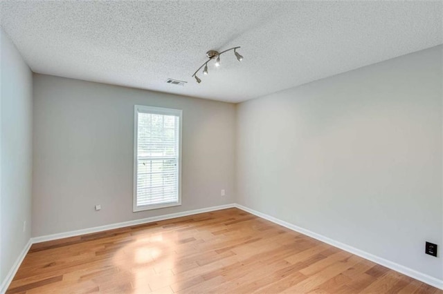 1227 Casper Ln, Winder, GA 30680 - empty room with light wood-style flooring, rail lighting, a textured ceiling, and baseboards