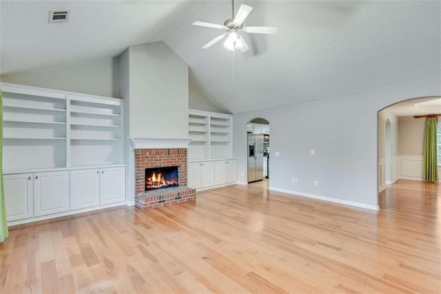 1227 Casper Ln, Winder, GA 30680 - unfurnished living room with arched walkways, a ceiling fan, built in shelves, light wood-style flooring, and a fireplace