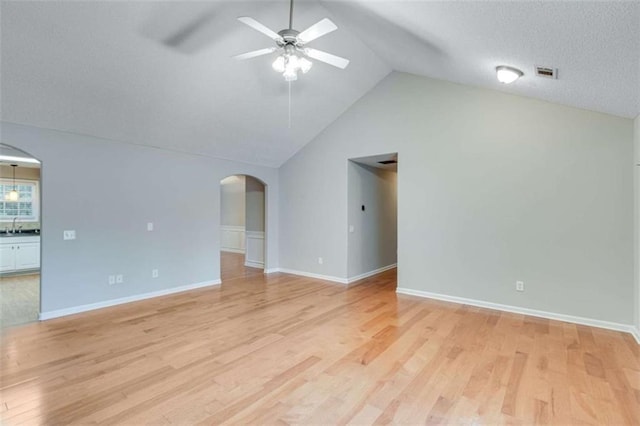 1227 Casper Ln, Winder, GA 30680 - unfurnished living room featuring arched walkways, ceiling fan, lofted ceiling, light wood-style floors, and baseboards