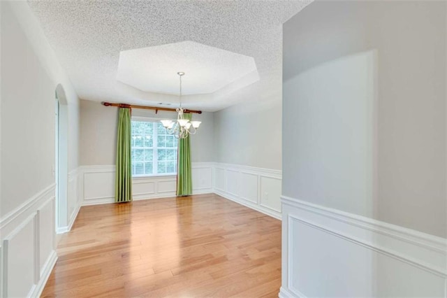 1227 Casper Ln, Winder, GA 30680 - empty room featuring a textured ceiling, a decorative wall, a chandelier, light wood finished floors, and a tray ceiling
