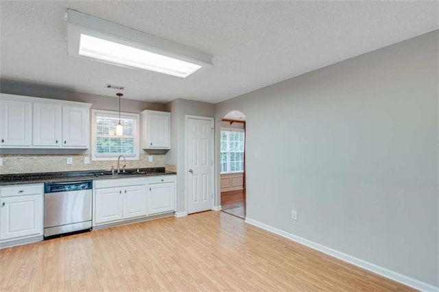 1227 Casper Ln, Winder, GA 30680 - kitchen featuring dishwasher, a sink, arched walkways, dark countertops, and light wood-style flooring