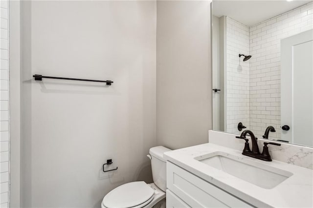 bathroom with vanity, toilet, and a tile shower