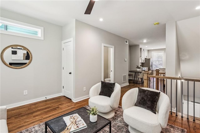 living area with dark hardwood / wood-style flooring and ceiling fan