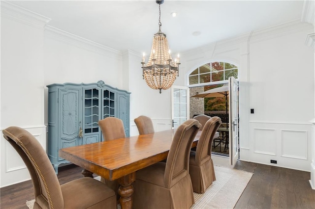 dining room featuring crown molding, a wainscoted wall, wood finished floors, and a decorative wall