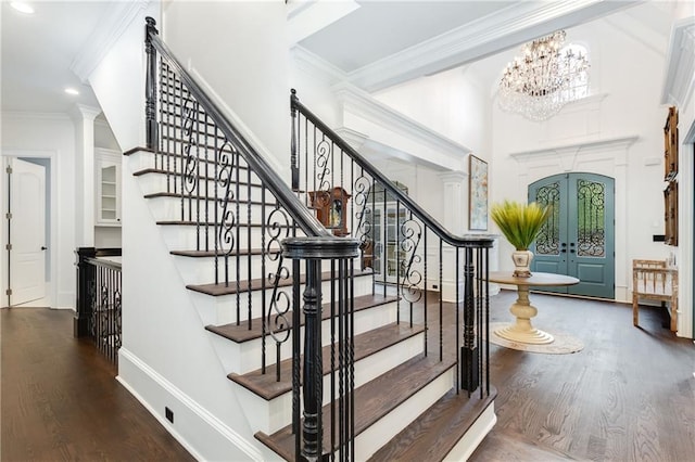 stairway featuring an inviting chandelier, wood finished floors, crown molding, and french doors