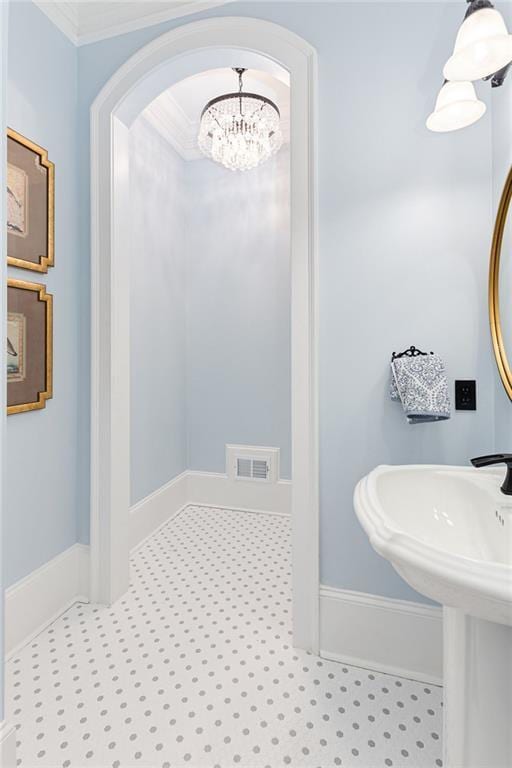 bathroom featuring baseboards, visible vents, and crown molding