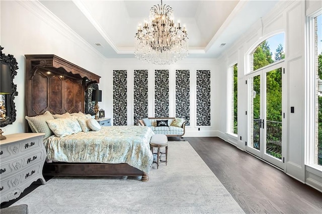 bedroom featuring a notable chandelier, a raised ceiling, ornamental molding, wood finished floors, and access to outside