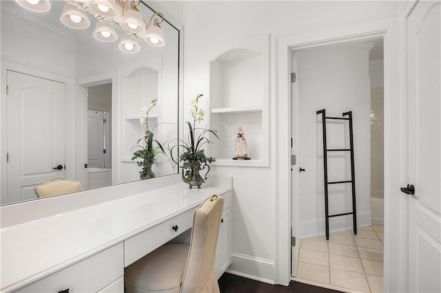 bathroom with built in features, baseboards, tile patterned floors, crown molding, and vanity