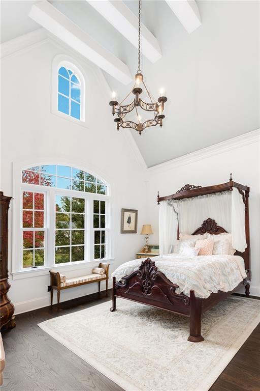 bedroom featuring high vaulted ceiling, multiple windows, an inviting chandelier, and wood finished floors