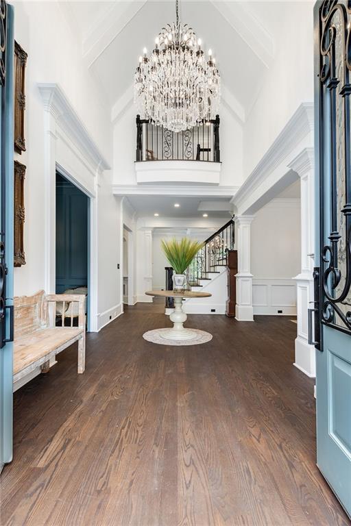 foyer with wood finished floors, a high ceiling, an inviting chandelier, and stairs