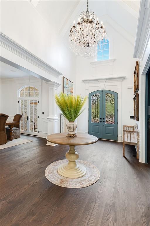 foyer entrance featuring high vaulted ceiling, french doors, a healthy amount of sunlight, and wood finished floors