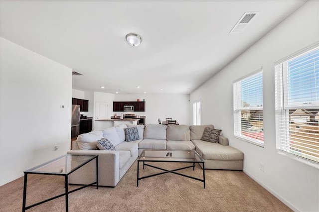 living room with light carpet, baseboards, and visible vents