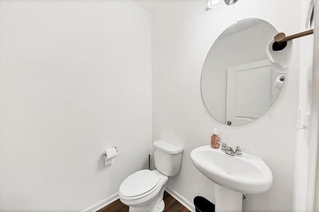 bathroom featuring toilet, baseboards, a sink, and wood finished floors