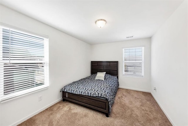 bedroom with baseboards, visible vents, and light colored carpet