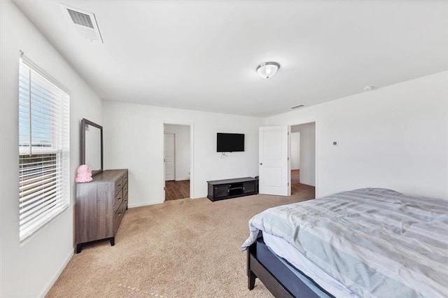 bedroom featuring visible vents, light carpet, and baseboards