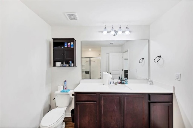 bathroom featuring toilet, a stall shower, vanity, and visible vents