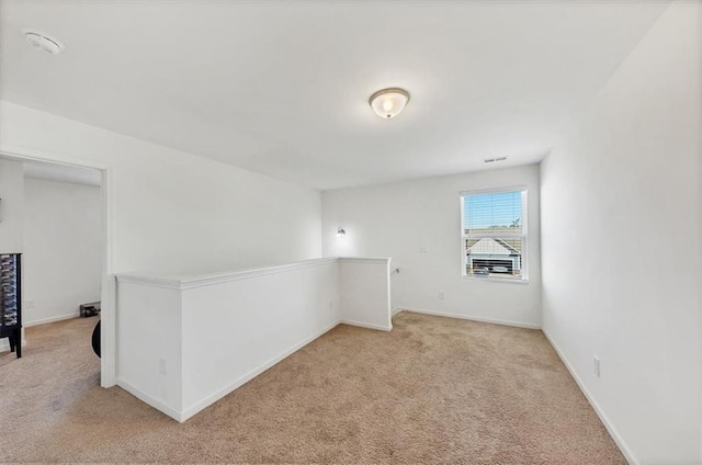 unfurnished room with baseboards and light colored carpet