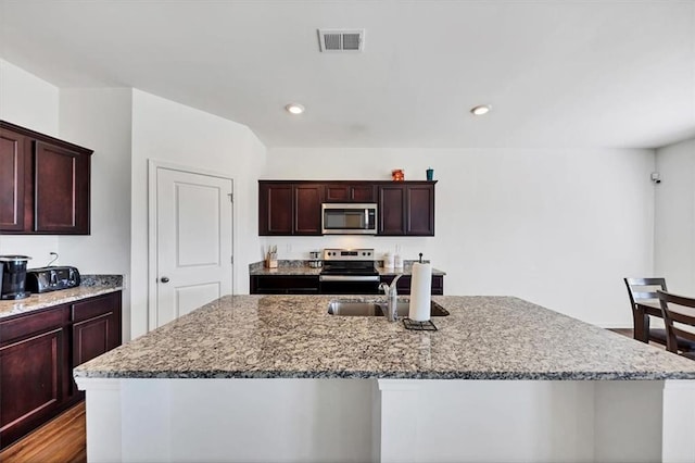 kitchen with appliances with stainless steel finishes, visible vents, a sink, and light stone countertops