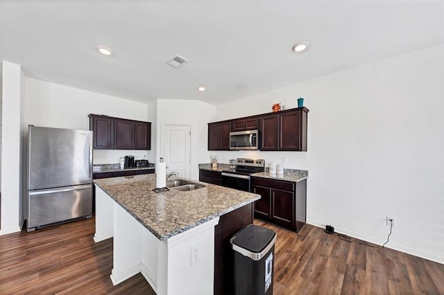 kitchen featuring stone counters, stainless steel appliances, dark wood-style flooring, a sink, and an island with sink