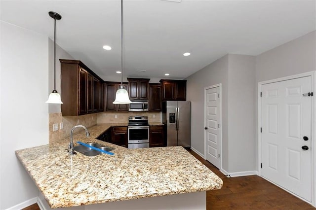 kitchen with stainless steel appliances, decorative light fixtures, kitchen peninsula, and sink